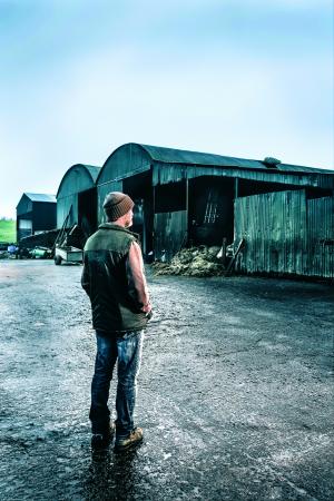 Image of a farmer standing in front of a tall shed